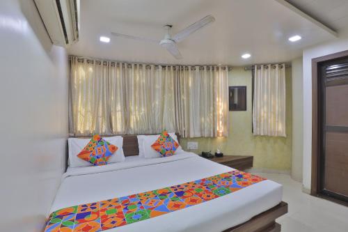 a bedroom with a large white bed with colorful pillows at new hotel ideal in Vadodara