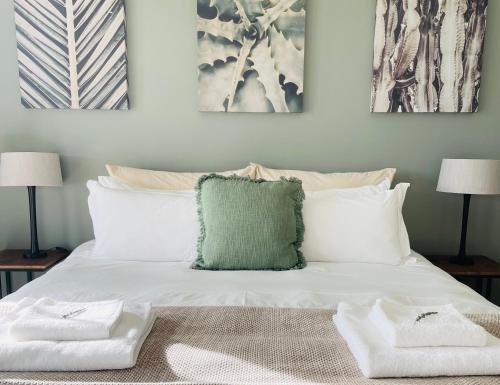 a white bed with a green pillow on it at Hilltop 39, Oubaai Golf Estate in Herolds Bay