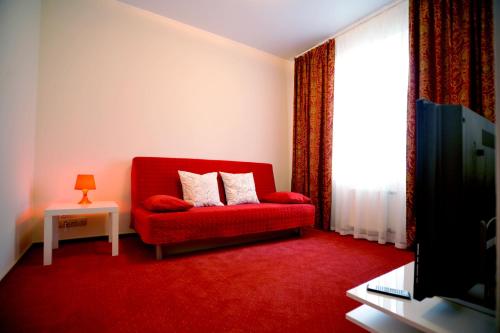 sala de estar con sofá rojo y ventana en Hotel Vintage Sheremetyevo, en Moscú