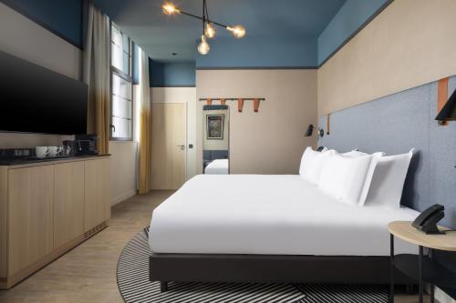a hotel room with a large bed and a tv at Hyatt Place Rouen in Rouen
