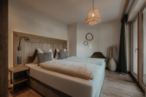 a bedroom with a large bed with a wooden headboard at FRÄULEIN NANNERL - Boutique Apart mit Saunahaus in Gerlos