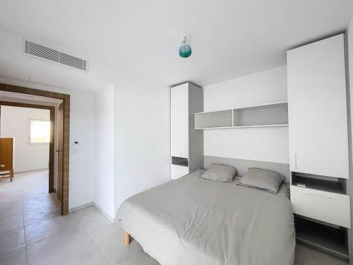 - une chambre avec un grand lit et des murs blancs dans l'établissement Grand appartement avec vue mer panoramique, à Calvi