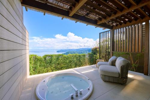 a room with a tub and chairs on a patio at Hotel Grand Bach Atami Crescendo in Atami