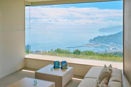 a living room with a large window overlooking the water at Hotel Grand Bach Atami Crescendo in Atami