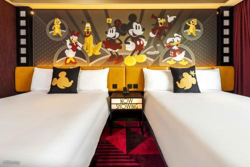 una camera con due letti e una parete con dipinti di topolini topolini di Disney's Hollywood Hotel a Hong Kong