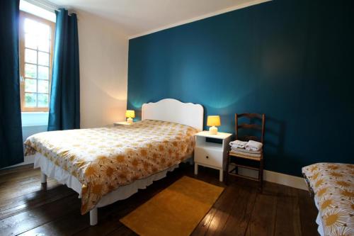 a bedroom with a bed and a blue wall at La ferme de lapeyrousse in Saint-Vitte-sur-Briance