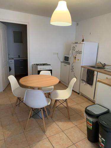 - une cuisine avec une table en bois et des chaises blanches dans l'établissement Studio tout équipé 2 à 4 personnes, à Saints
