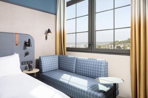 a hotel room with a couch and a bed and windows at Hyatt Place Rouen in Rouen