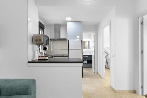 a kitchen with white cabinets and a counter top at Apartamentos Bellamar in Barbate