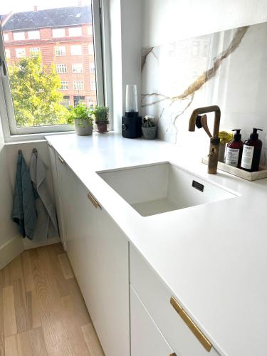 a white kitchen with a sink and a window at Lys, charmerende, tæt på strand in Hellerup