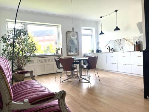 a kitchen and living room with a table and chairs at Lys, charmerende, tæt på strand in Hellerup