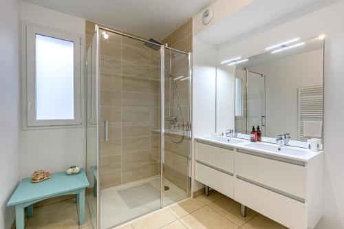 une salle de bain avec une douche en verre et un lavabo dans l'établissement Le Loarwenn - Bel appt avec terrasse et parking, à Vannes