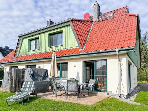 una casa con techo naranja con sillas y sombrilla en Schifferkaten, en Pruchten