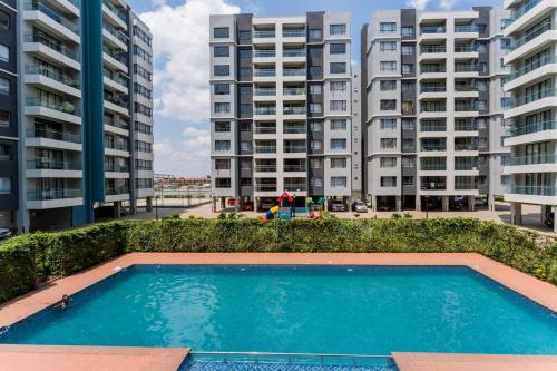 ナイロビにあるKapri Nairobi 2BR Suite w Pool Gym near JKIA SGRの一部のアパートメントビルの前にスイミングプールがあります。
