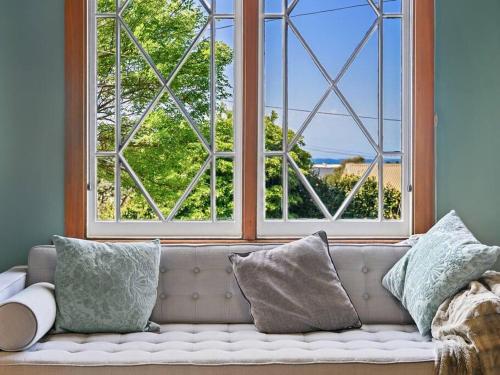 a couch in a room with a large window at Santos 20th century cottage in South Burnie