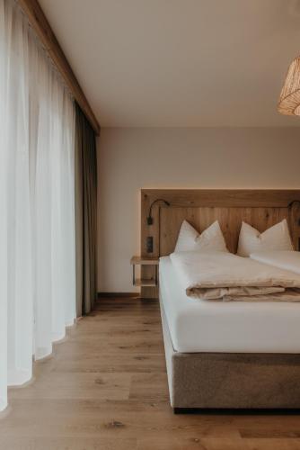 a bedroom with a bed with white sheets and a window at FRÄULEIN NANNERL - Boutique Apart mit Saunahaus in Gerlos