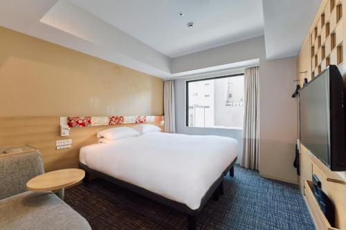 a hotel room with a large bed and a flat screen tv at Hotel Grand Bach Kyoto Select in Kyoto