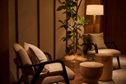 a living room with two chairs and a potted plant at Hotel Grand Bach Kyoto Select in Kyoto