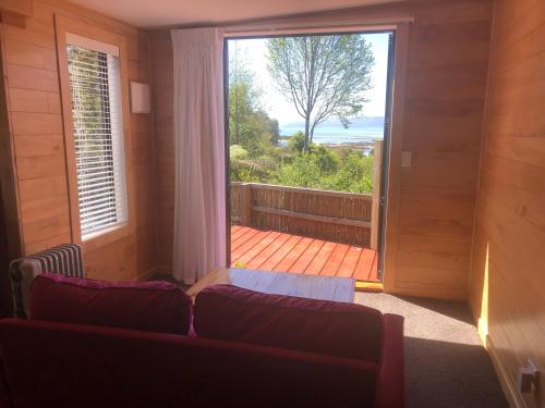 a living room with a couch and a large window at Heron Hideaway at First Light Rangihaeata Retreat in Rangihaeata