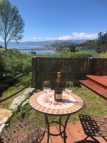 a table with a bottle of wine and two glasses at Heron Hideaway at First Light Rangihaeata Retreat in Rangihaeata