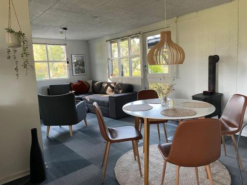 a living room with a couch and a table and chairs at Aneks i rolige omgivelser-adgang til pool og sauna in Avlum