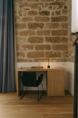 a desk and a chair in a room with a brick wall at Spasimo Hôtellerie in Palermo
