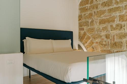 a bedroom with a bed and a stone wall at Spasimo Hôtellerie in Palermo