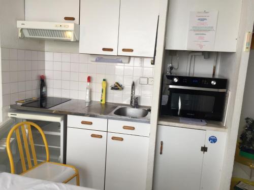 une petite cuisine avec des armoires blanches et un évier dans l'établissement Résidence FACE SUD LA MONGIE, à La Mongie