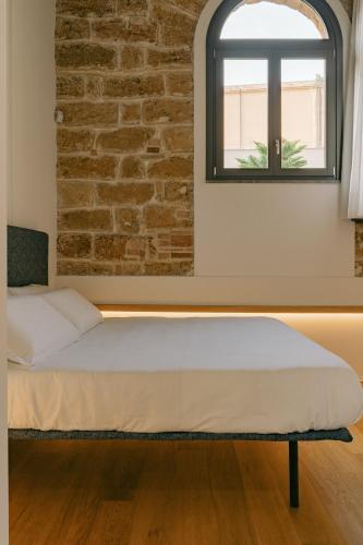 a bed in a room with a brick wall at Spasimo Hôtellerie in Palermo