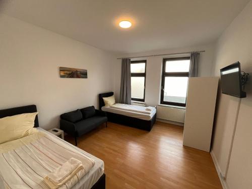 a bedroom with a bed and a couch and a chair at Zentrale 2-Zimmer-Monteurwohnung in Neumünster in Neumünster