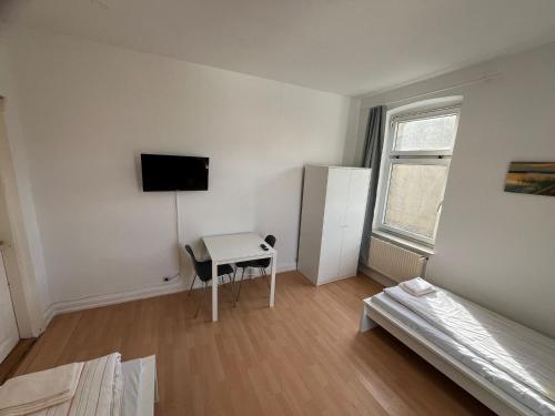 a white room with a desk and a television in it at Zentrale 2-Zimmer-Monteurwohnung in Neumünster in Neumünster