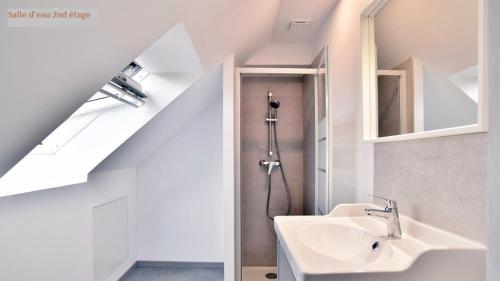 a white bathroom with a sink and a mirror at Cana in Pleslin-Trigavou