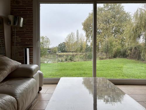 a living room with a glass table in front of a window at Le parc de Gouts in Aiguillon