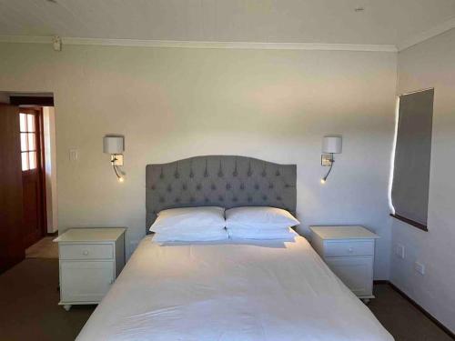 a bedroom with a large white bed with two night stands at River Paradise in Bushmans River Village