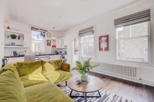 a living room with a yellow couch and a table at Stylish flat in Shoreditch, Private Roof Terrace in London
