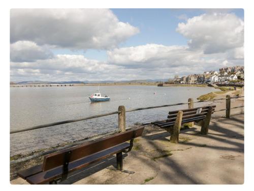 a boat in a body of water with two benches at Sunnycote in Arnside