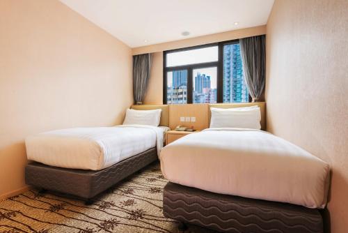 two beds in a hotel room with a window at Metropark Hotel Mongkok in Hong Kong
