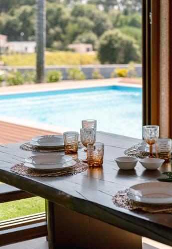 a table with plates and glasses and a swimming pool at Belo Encanto in Felgueiras