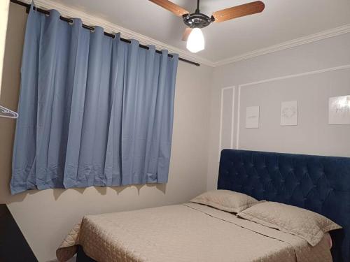 a bedroom with a blue bed and a ceiling fan at apto simples,3min centro, 3 min da Unimed com wifi in Araçatuba