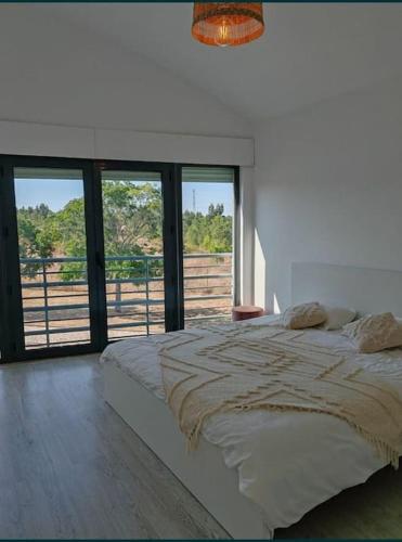 a bedroom with a large bed with a large window at Villa Palmela Resort V5 Piscina privado in Quinta do Anjo