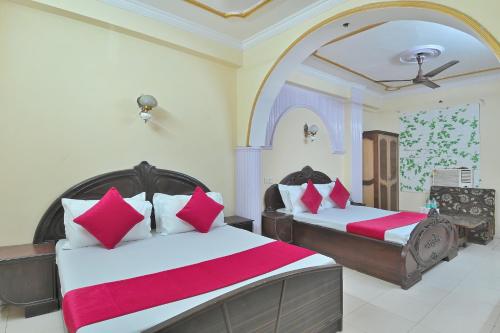 a bedroom with two beds with red and white pillows at Hotel Ashoka Continental in New Delhi