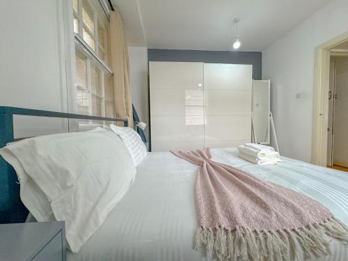a bedroom with a white bed with a pink blanket on it at Gower street residences in London