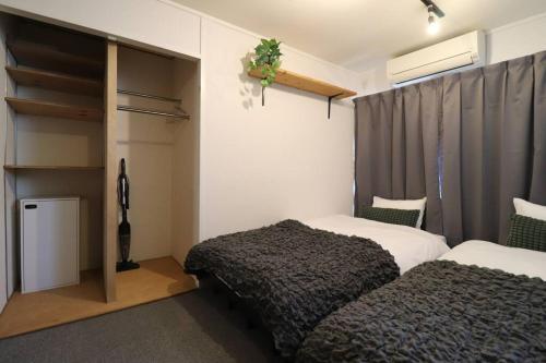 une chambre avec deux lits et un placard dans l'établissement urban stay 今泉, à Susakiuramachi