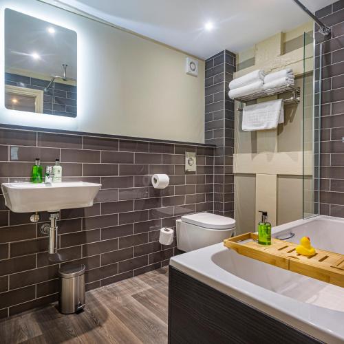 a bathroom with a tub and a sink and a toilet at The Castle Of Brecon Hotel, Brecon, Powys - The Coaching Inn Group in Brecon
