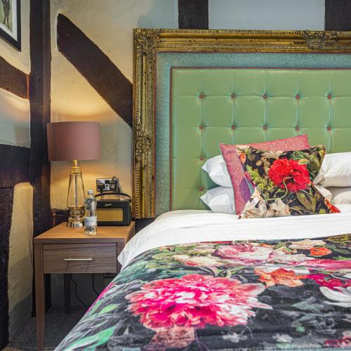 a bedroom with a bed with a green headboard at The Castle Of Brecon Hotel, Brecon, Powys - The Coaching Inn Group in Brecon