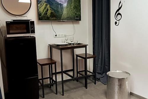 une petite table avec deux tabourets et un four micro-ondes dans l'établissement Le mini loft - studio, à Nevers