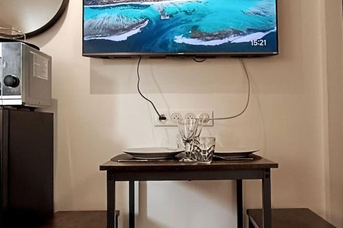 une table avec une télévision suspendue au mur dans l'établissement Le mini loft - studio, à Nevers