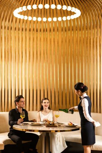 a man and woman sitting at a table with wine glasses at Radisson Blu Ha Long Bay in Ha Long