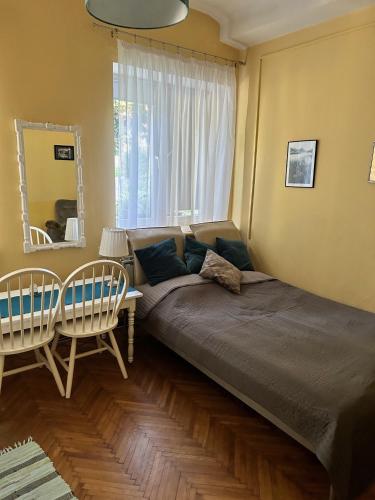 a bedroom with a bed and two chairs and a window at Apartament u Maliny in Krynica Zdrój
