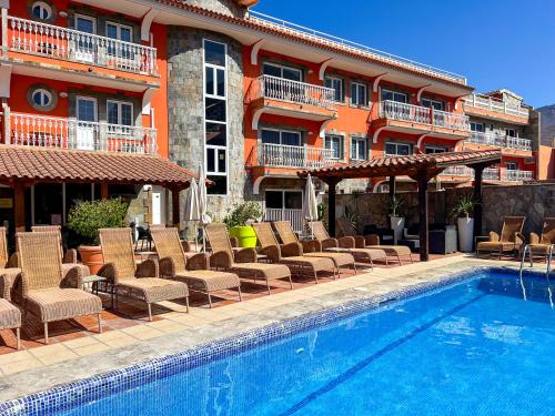 a swimming pool with chairs and a hotel at Hotel La Aldea Suites in La Aldea de San Nicolas